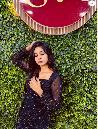 Black dotted dress photographed against the Ishal Dresses foliage wall